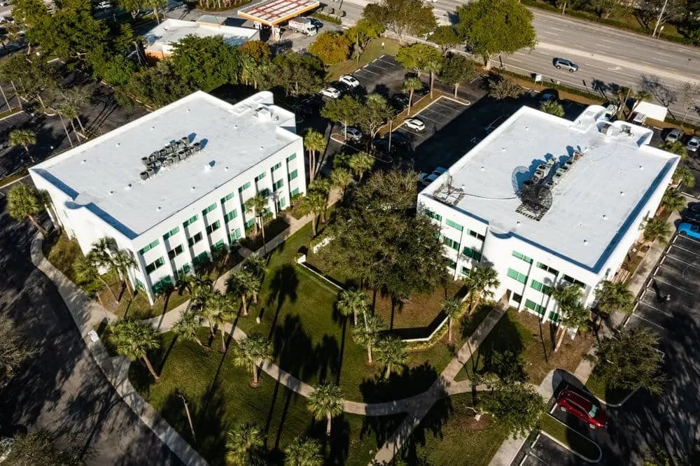 Aerial view of a commercial office building with a white flat roof