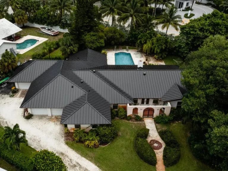 Home with a black standing seam metal roof and pool