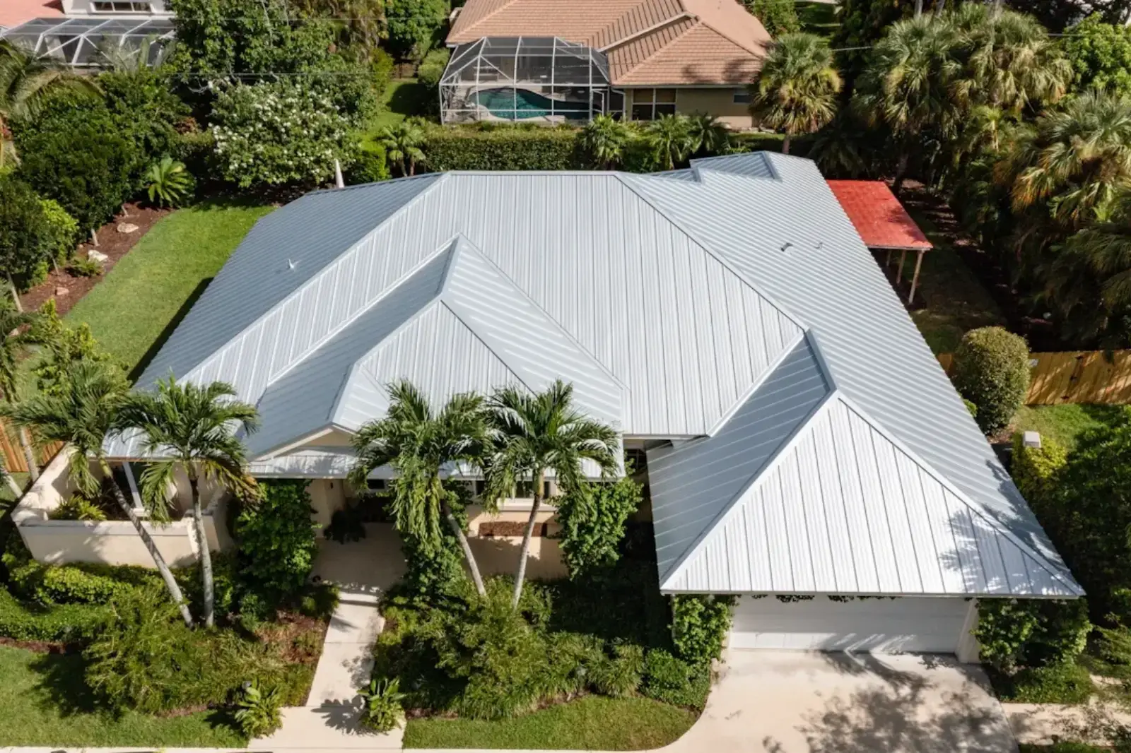 Aerial view of a home with a gray metal roof and screened pool cage