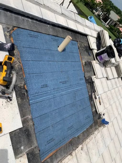 Roofers installing blue synthetic underlayment on a roof deck